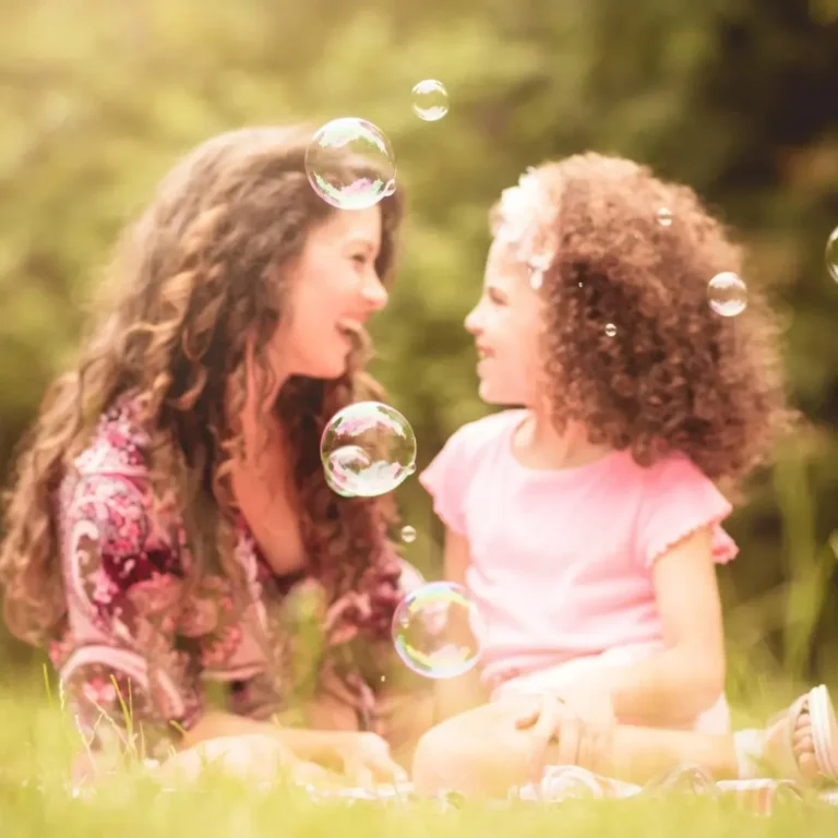 A mother and daughter spending quality time together blowing bubbles.